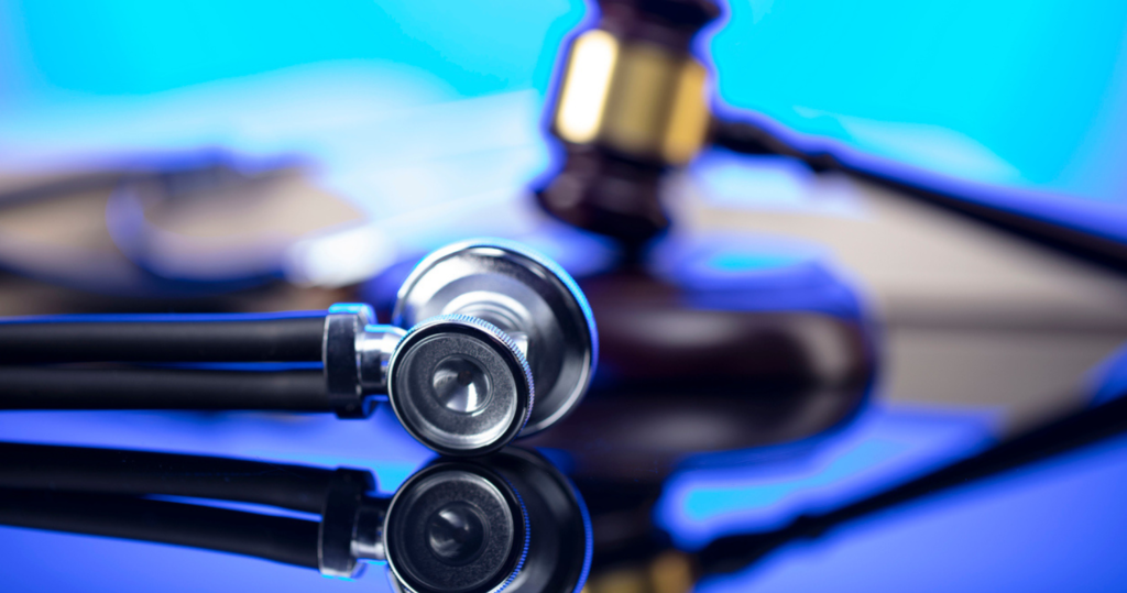 Gavel, legal code and stethoscope on the glass table. Blue light.