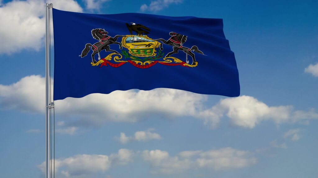 Flag of Pennsylvania blowing in the win against a blue sky